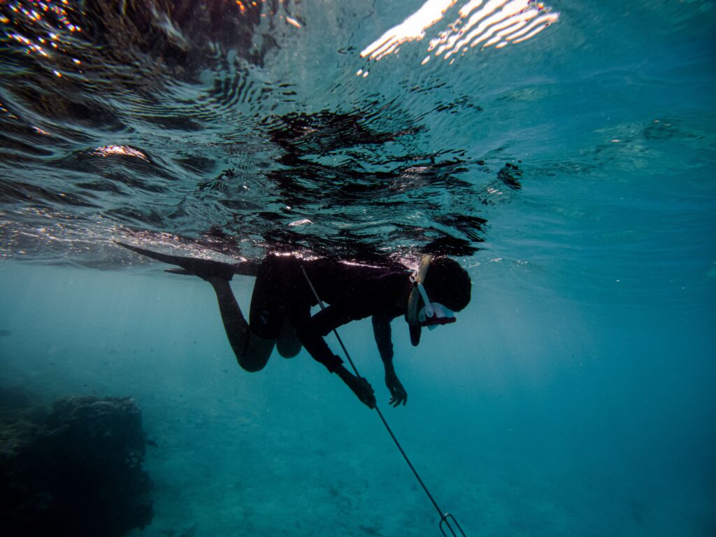 man in black wet suit swimming in water